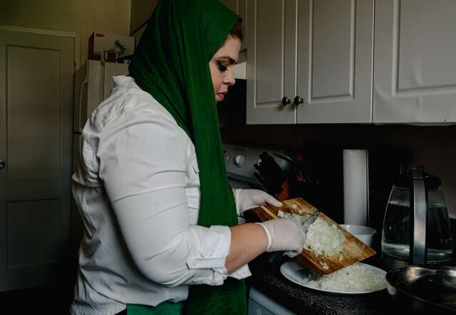 A woman wearing a hijab cooking food in her kitchen